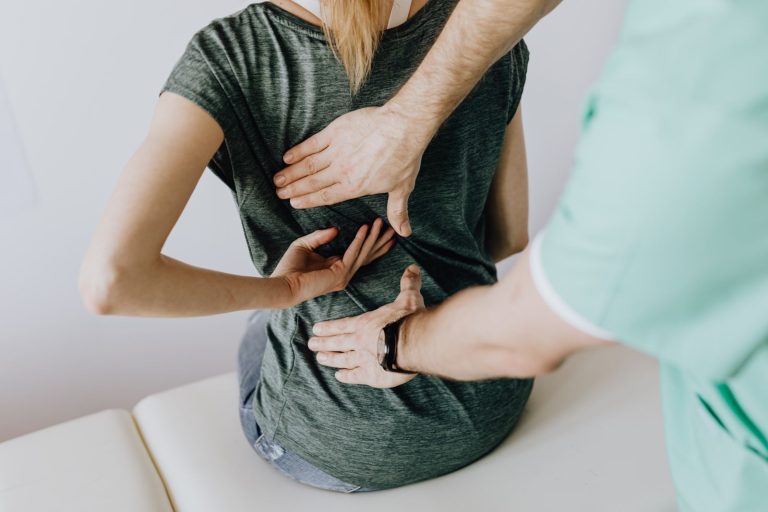 Mains d'un praticien posées sur le dos d'une patiente assise en cabinet